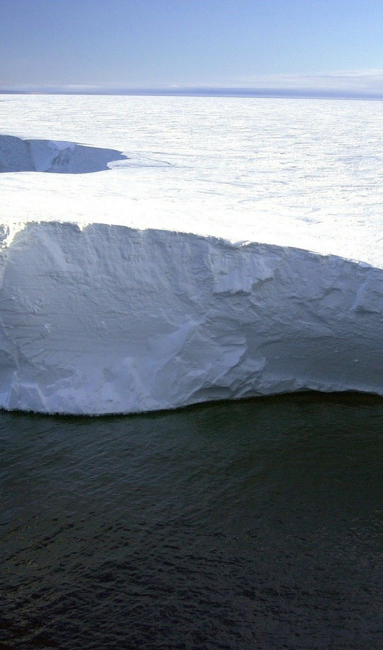 A huge white area of ice, with cliffs by the sea