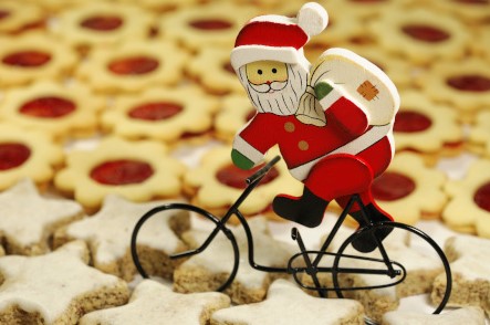 Weihnachtsmann auf einem Fahrrad. Er fährt über einen Kekshaufen