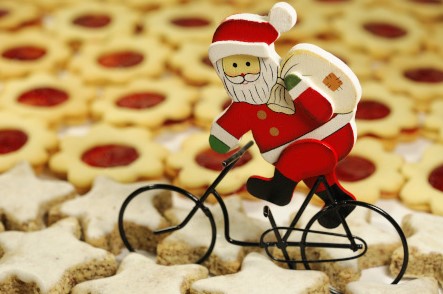 Weihnachtsmann auf einem Fahrrad. Er fährt über einen Kekshaufen