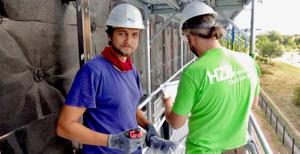 Zwei Forscher sind auf einer Baustelle und arbeiten an einer Photovoltaik Fassade.