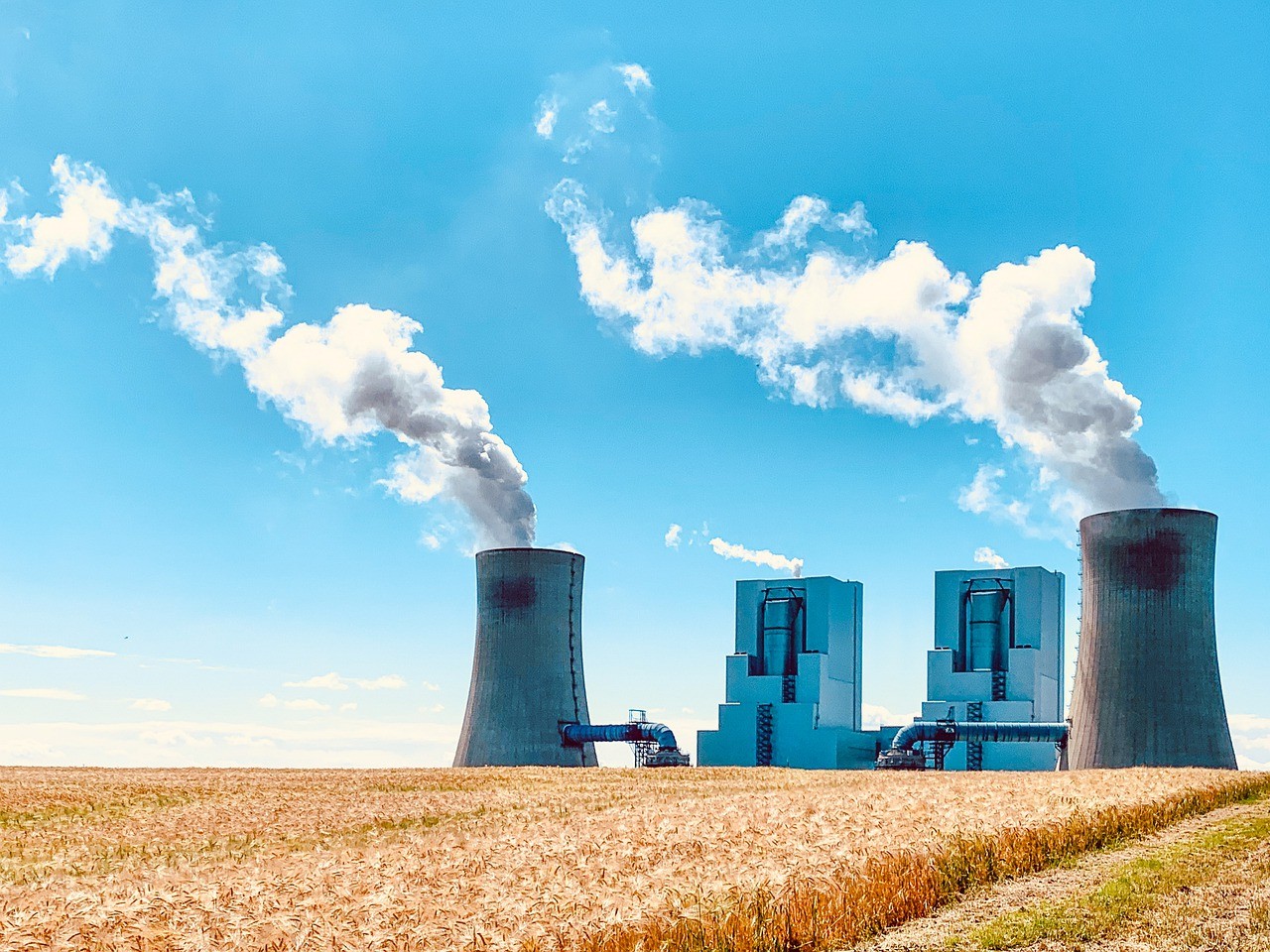 Kraftwerk auf Stoppelfeld vor blauem Himmel