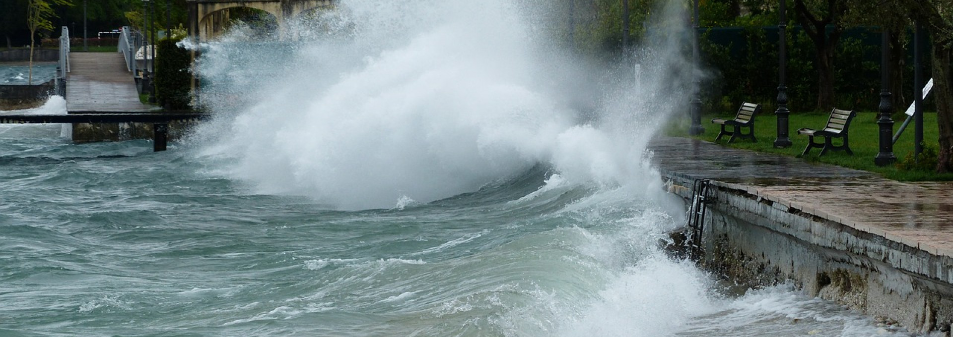 Eine große Welle schlägt gegen eine Uferpromenade