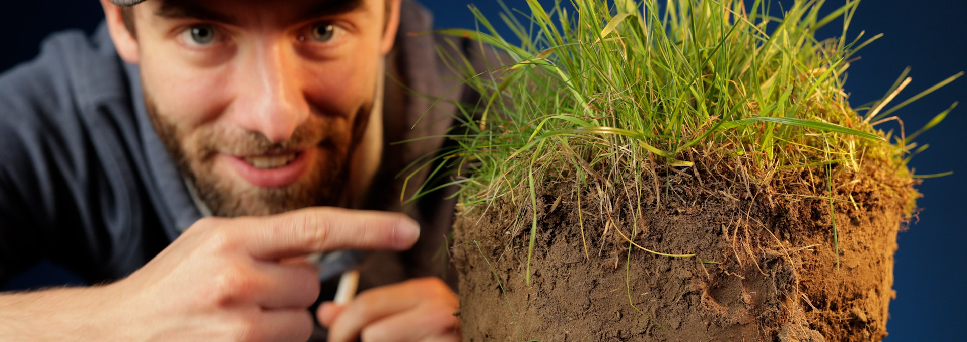 Standbild aus dem Film: Unser YouTuber mit einem ausgestochenen Stück Boden, wo oben das Gras rauswächst.