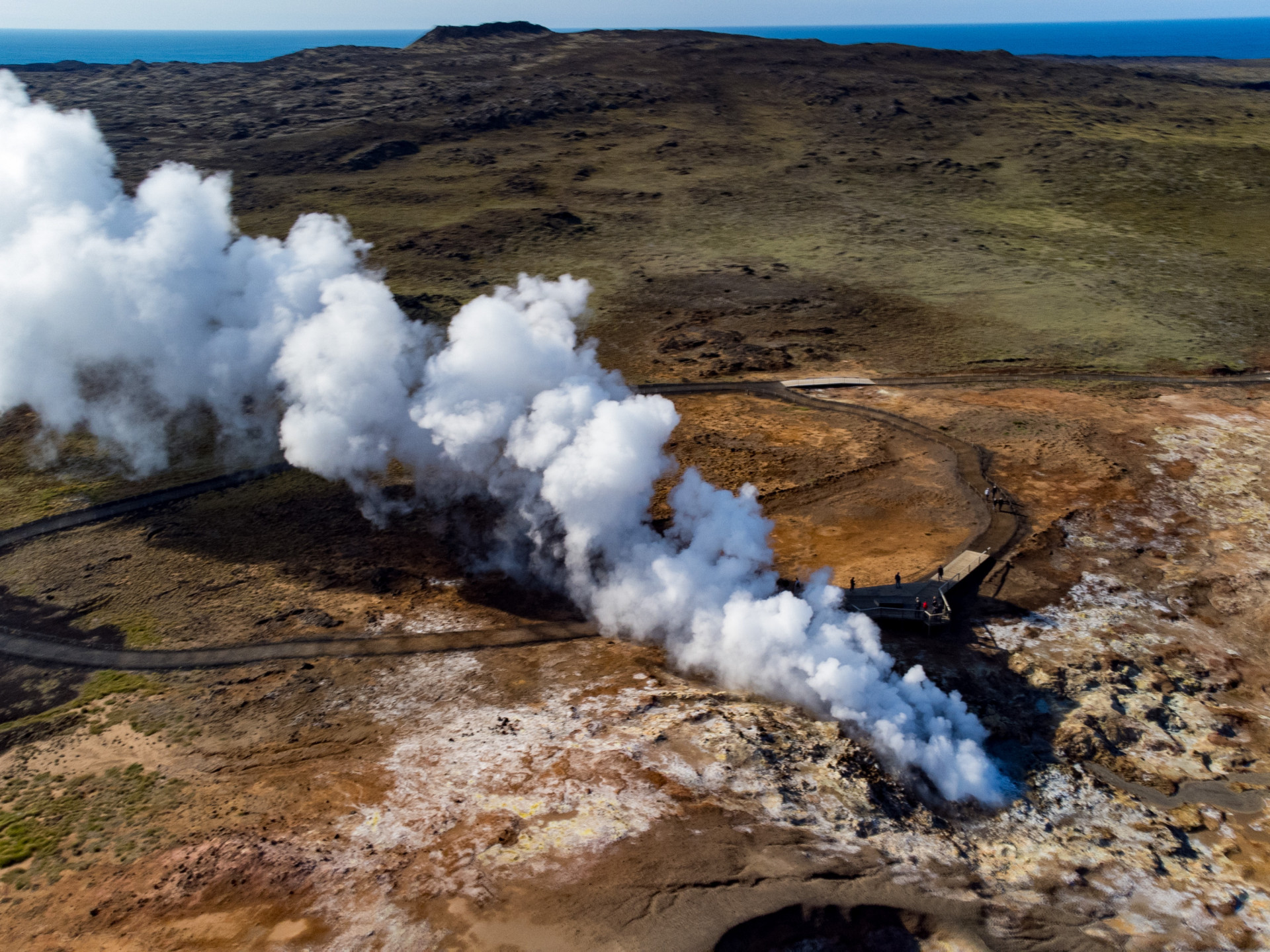 Luftaufnahme eines geothermischen Gebiets in Island mit Dampfquellen und heißen Quellen, umgeben von farbenprächtiger Minerallandschaft