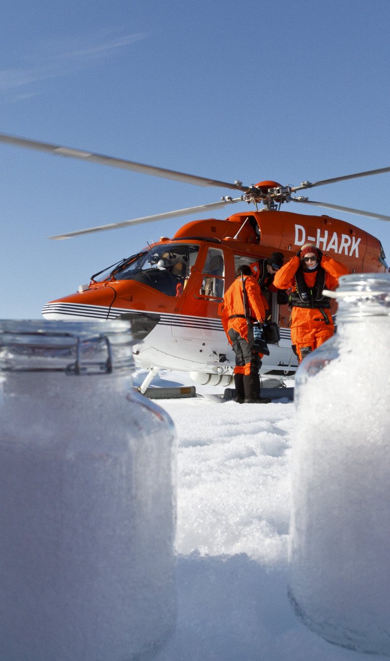 Samples of snow in mason jars with a red helicopter in the background