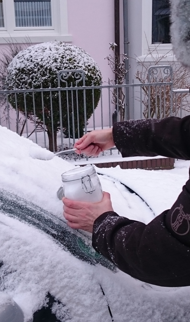 Scientist in winter coat collecting snow from a car