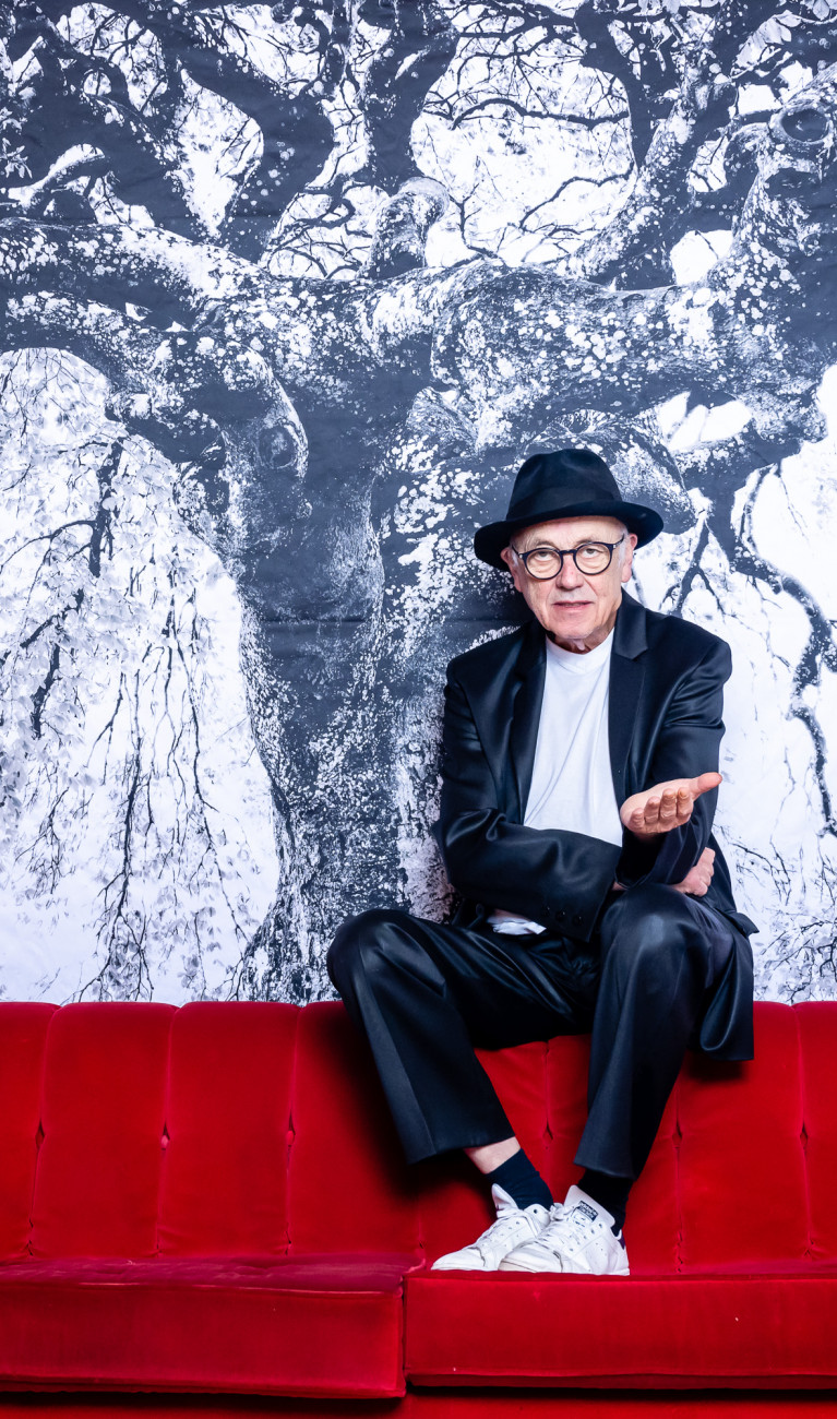 Fotograf und Künstler Horst Wackerbarth sitzt auf der roten Couch