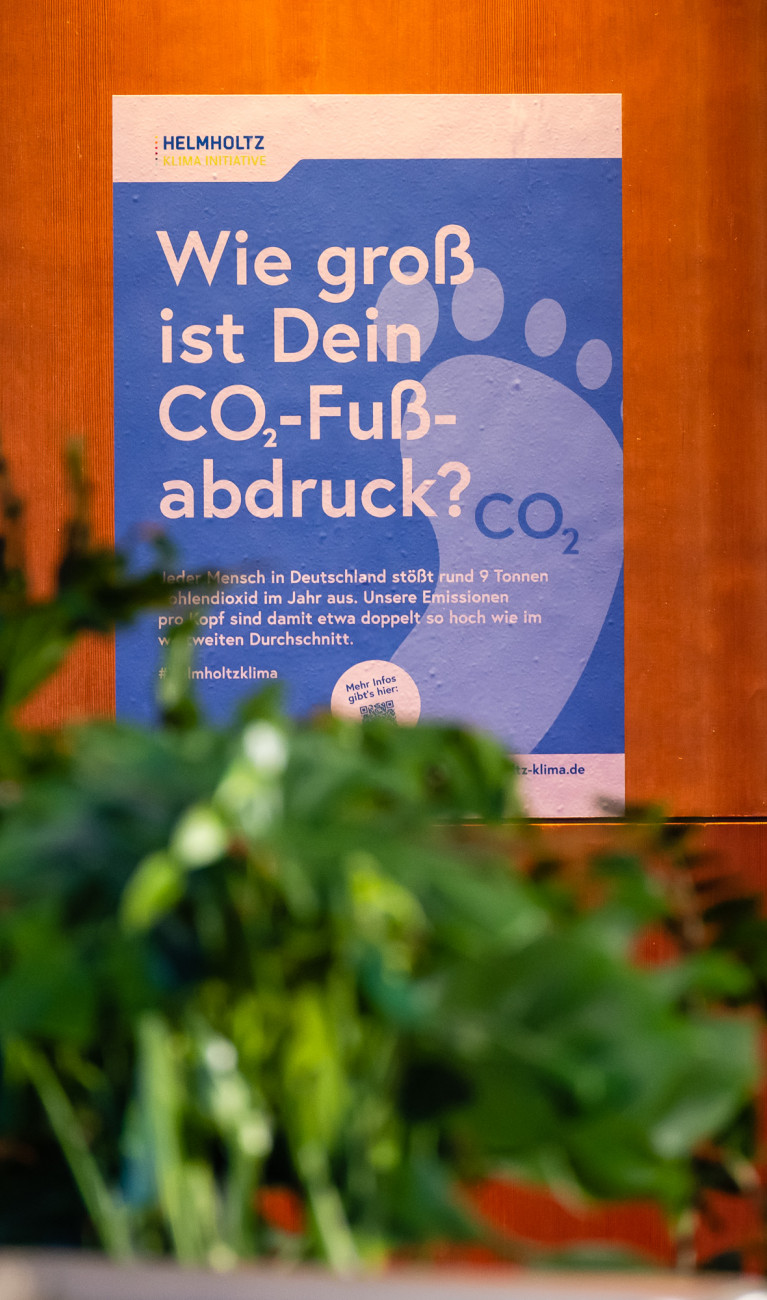 Das Plakat "Wie gross ist dein CO2-Fussabdruck" ist an einer Wand angebracht