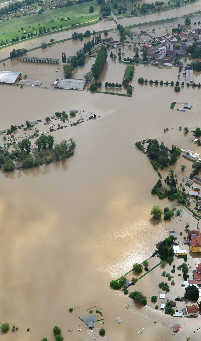 Mit Hochwasser überfluteter Landschaftszug. Häuser und Straßen stehen unter Wasser.