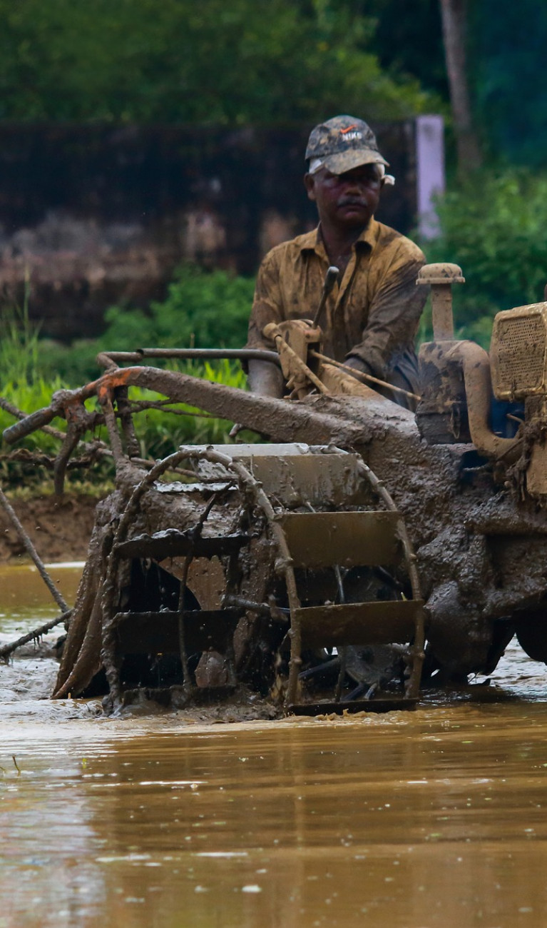 Two men with a tractor wade through a flooded area