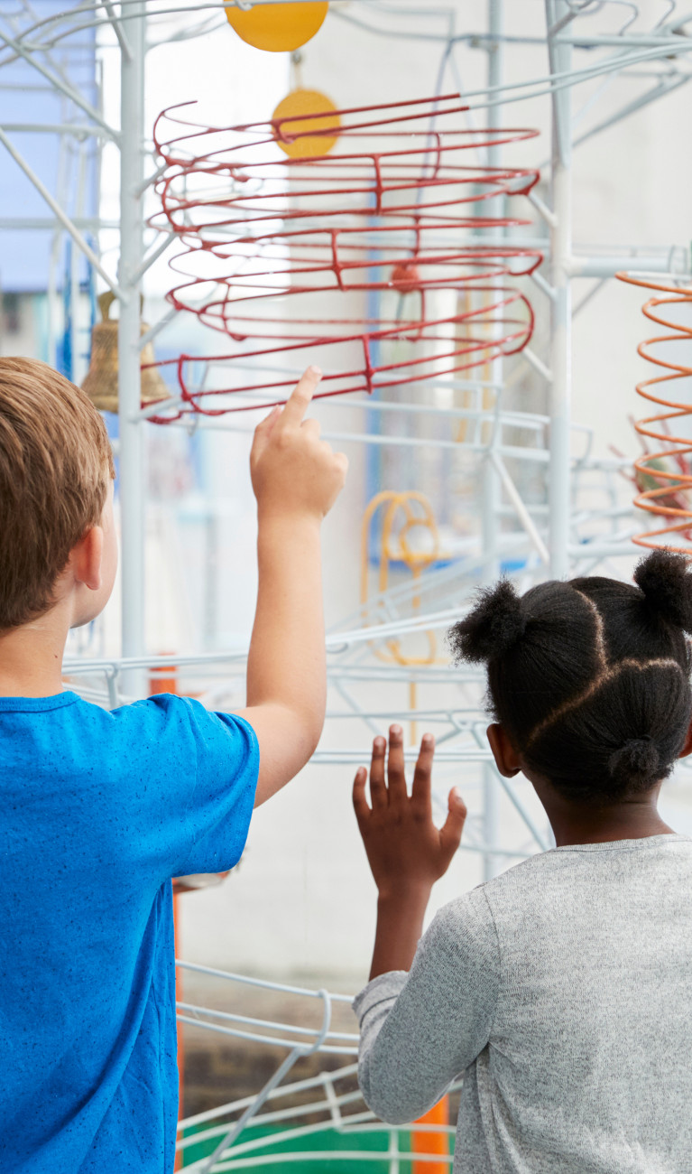 Two kids looking at a science exhibit, back view