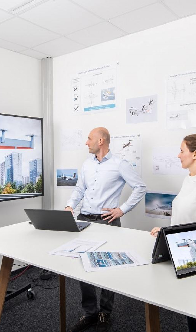 Three scientists in front of monitors and laptops discussing aircraft concepts.