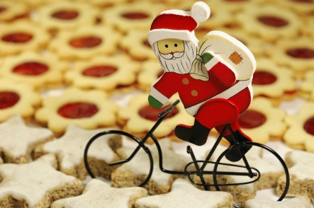 Weihnachtsmann auf einem Fahrrad. Er fährt über einen Kekshaufen.