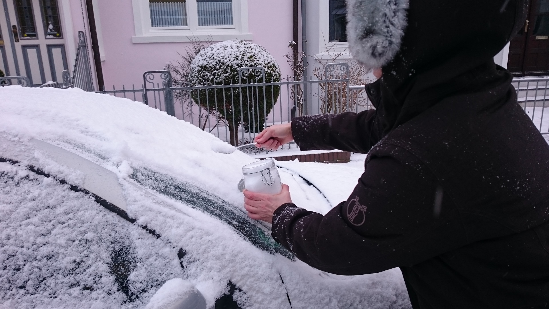 Scientist in winter coat collecting snow from a car