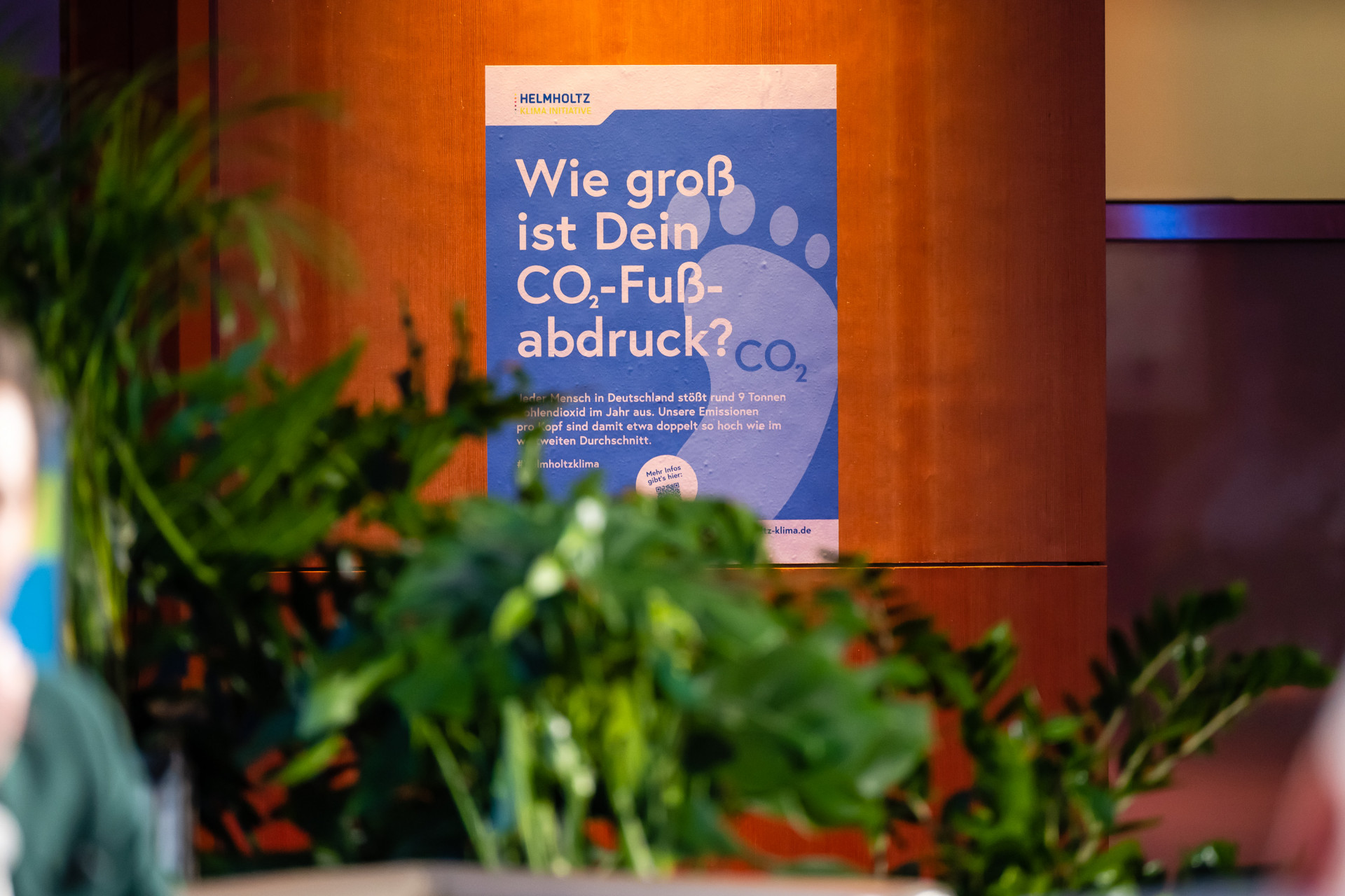 Das Plakat "Wie gross ist dein CO2-Fussabdruck" ist an einer Wand angebracht