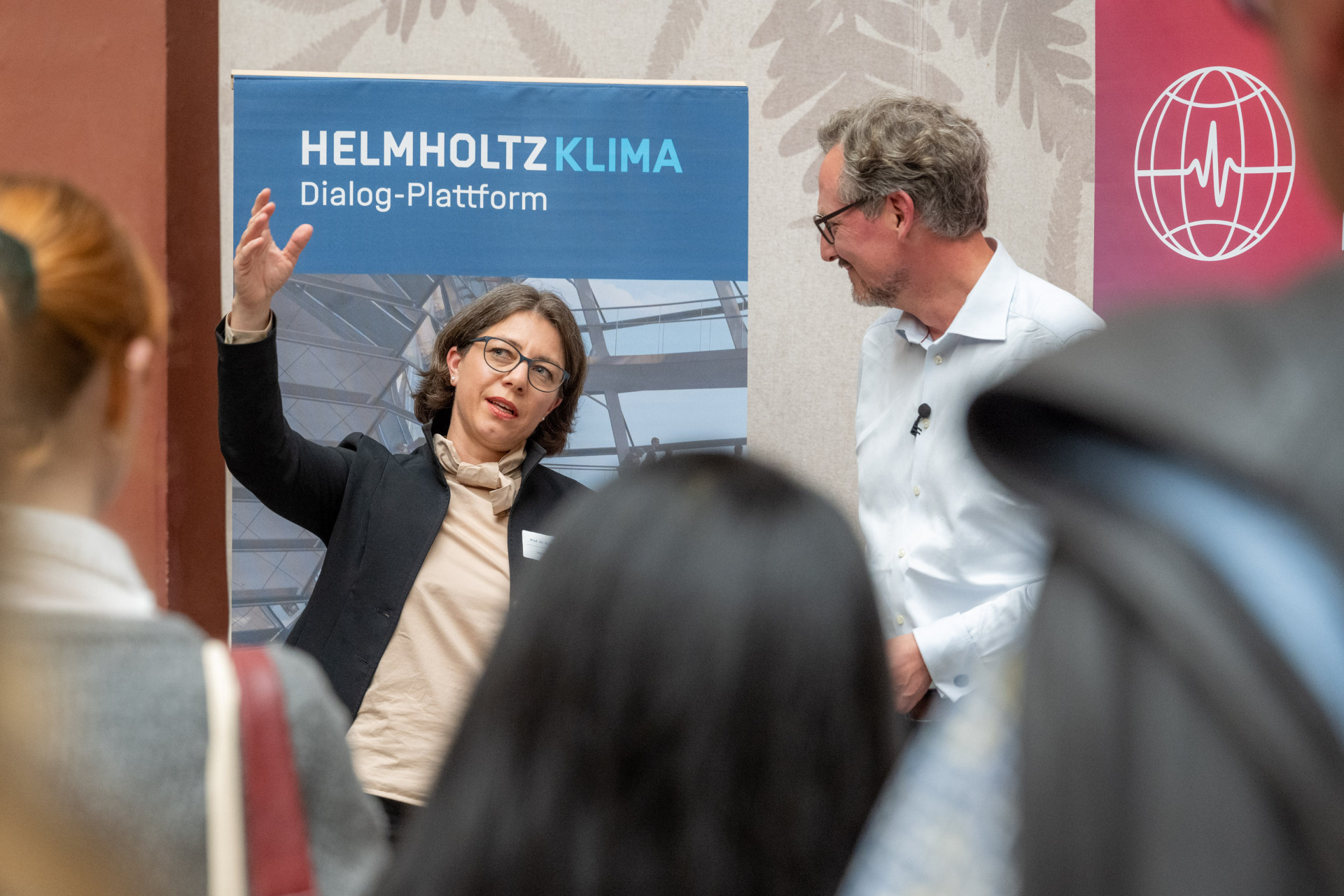 Zwei Personen im Austausch vor Publikum.