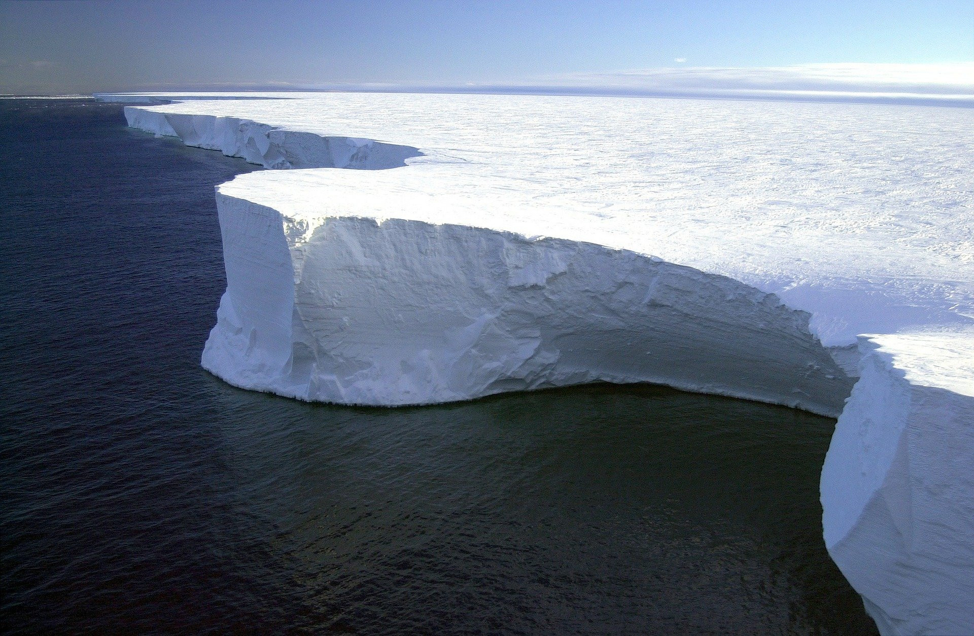Ein große weiße Eisfläche ragt aus dem dunklen Meer