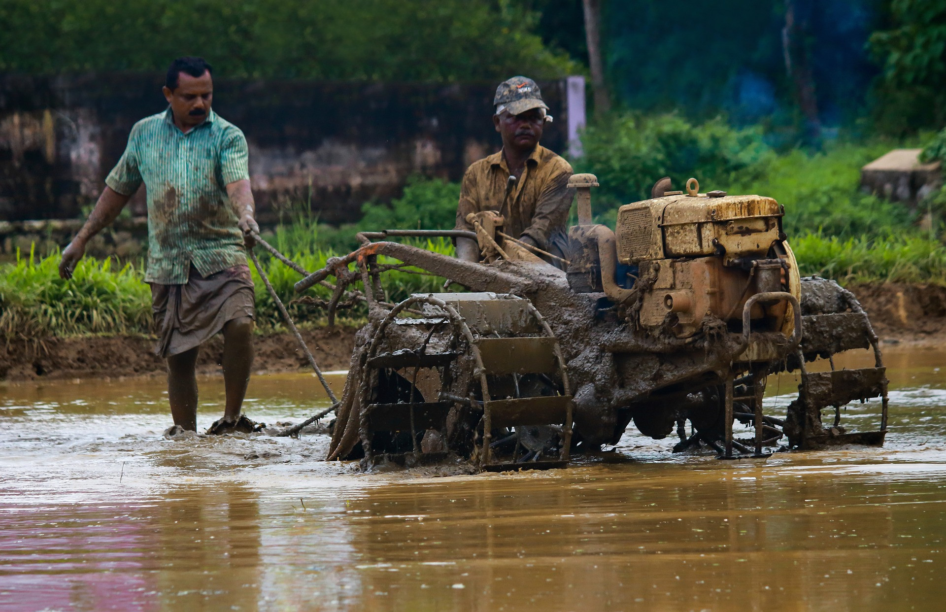 Two men with a tractor wade through a flooded area