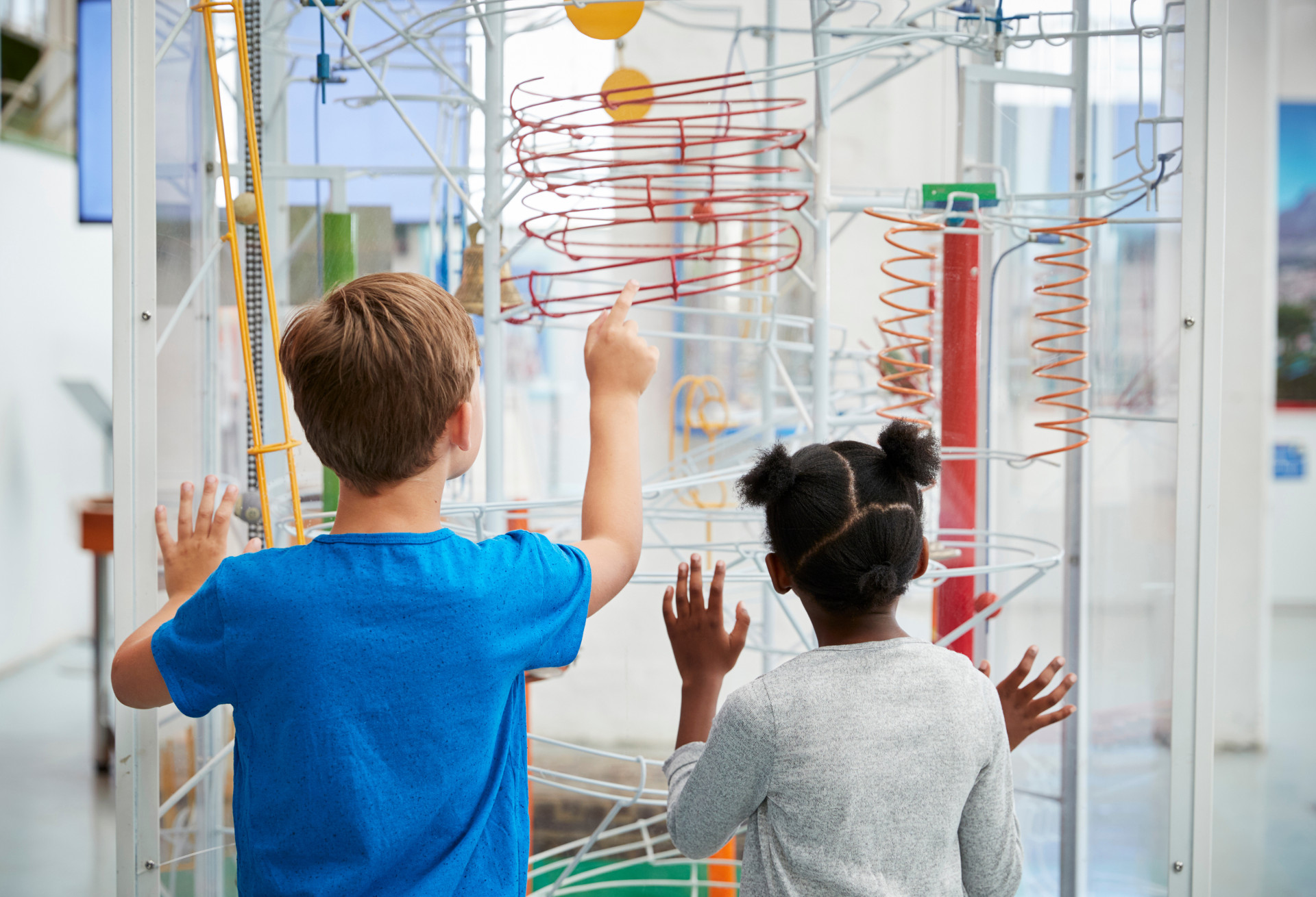 Two kids looking at a science exhibit, back view