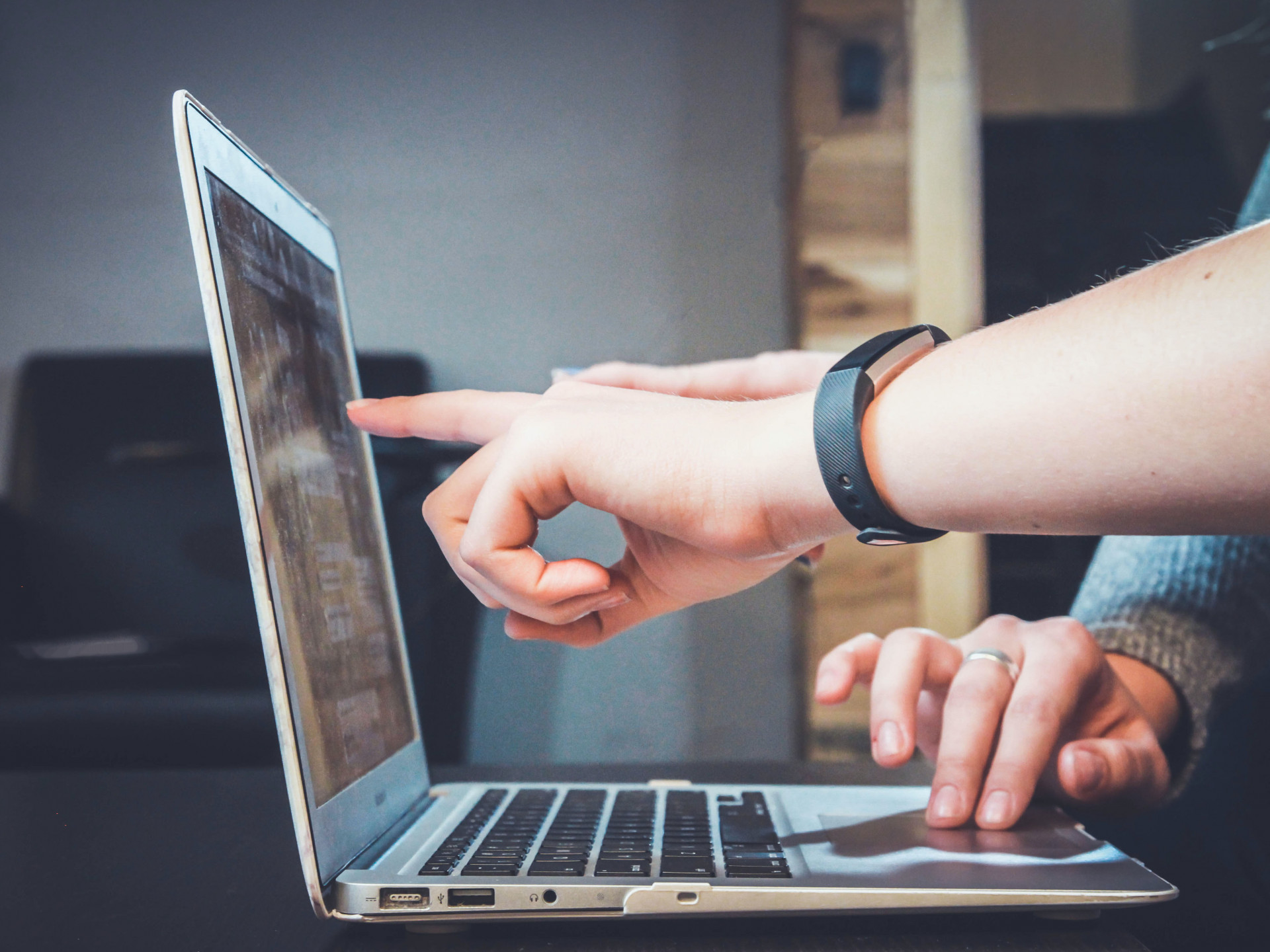 Personen zeigen mit dem Finger auf Laptop-Bildschirm