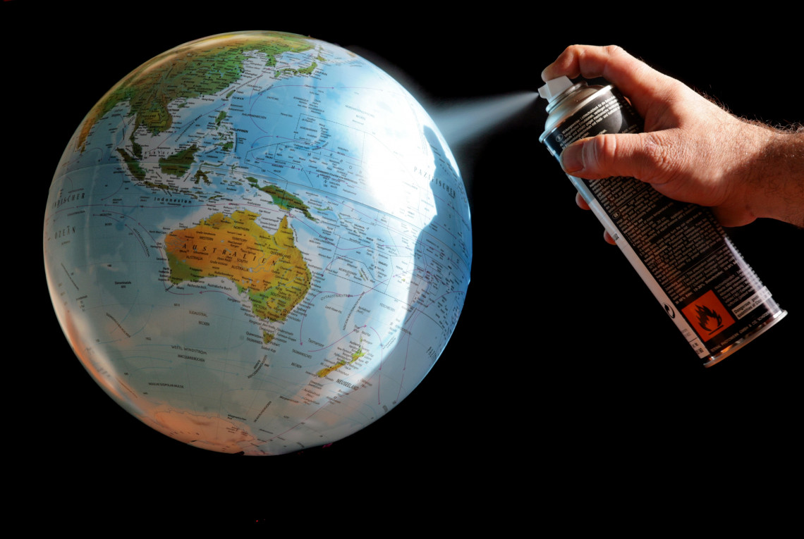 Eine Person besprüht mit einer Sprayflasche einen Globus.