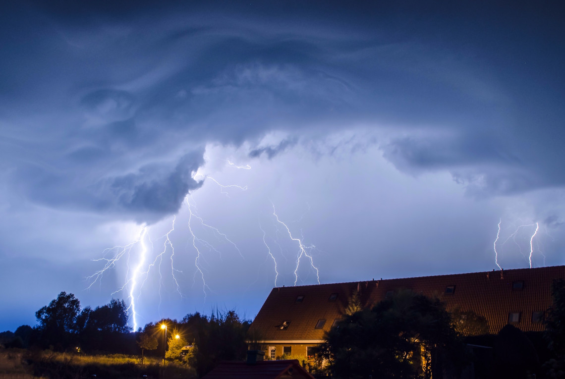 Dunkler Himmel mit Blitz und Donner. Im Vordergrund steht ein Wohnhaus.