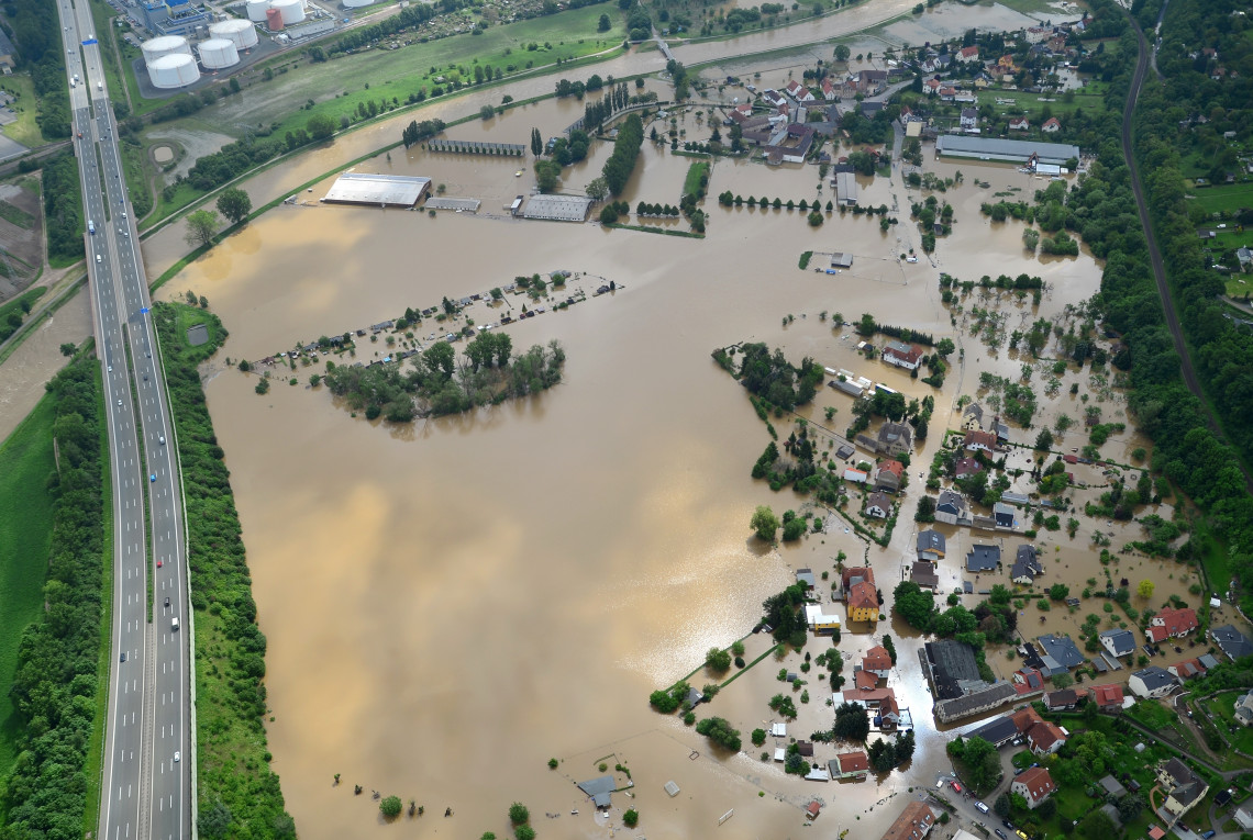 Mit Hochwasser überfluteter Landschaftszug. Häuser und Straßen stehen unter Wasser.