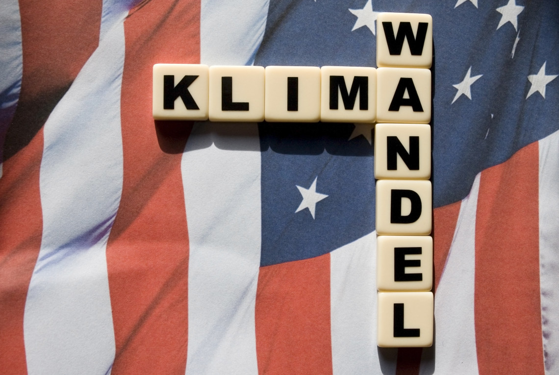 Amerikanische Flagge auf der in Buchstabenwürfel das Wort "Klimawandel" steht