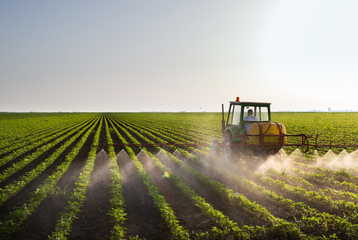 Ein Traktor sprüht Pestizide auf einem landwirtschaftlichen Feld