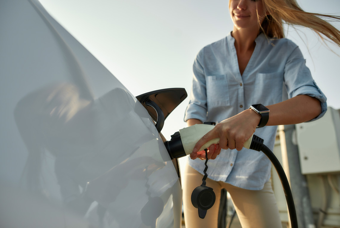 Eine Frau lädt ein Elektroauto draußen auf