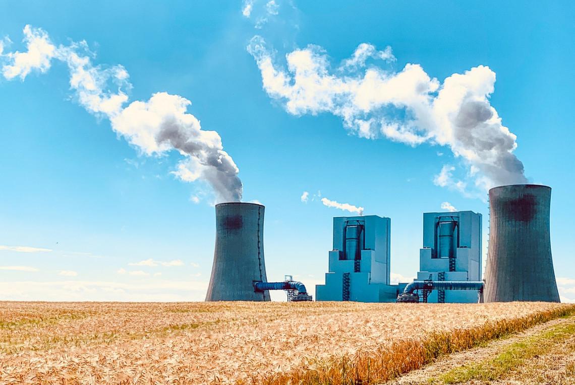 Kraftwerk auf Stoppelfeld vor blauem Himmel