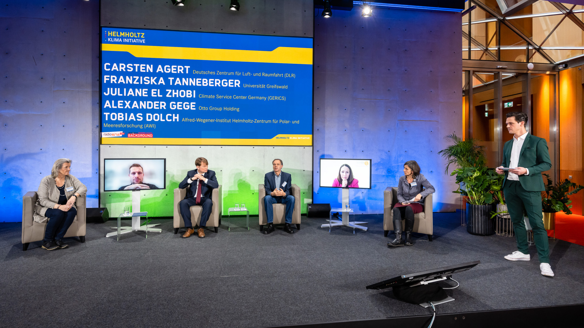 Podiumsteilnehmer:innen sitzen auf der Bühne