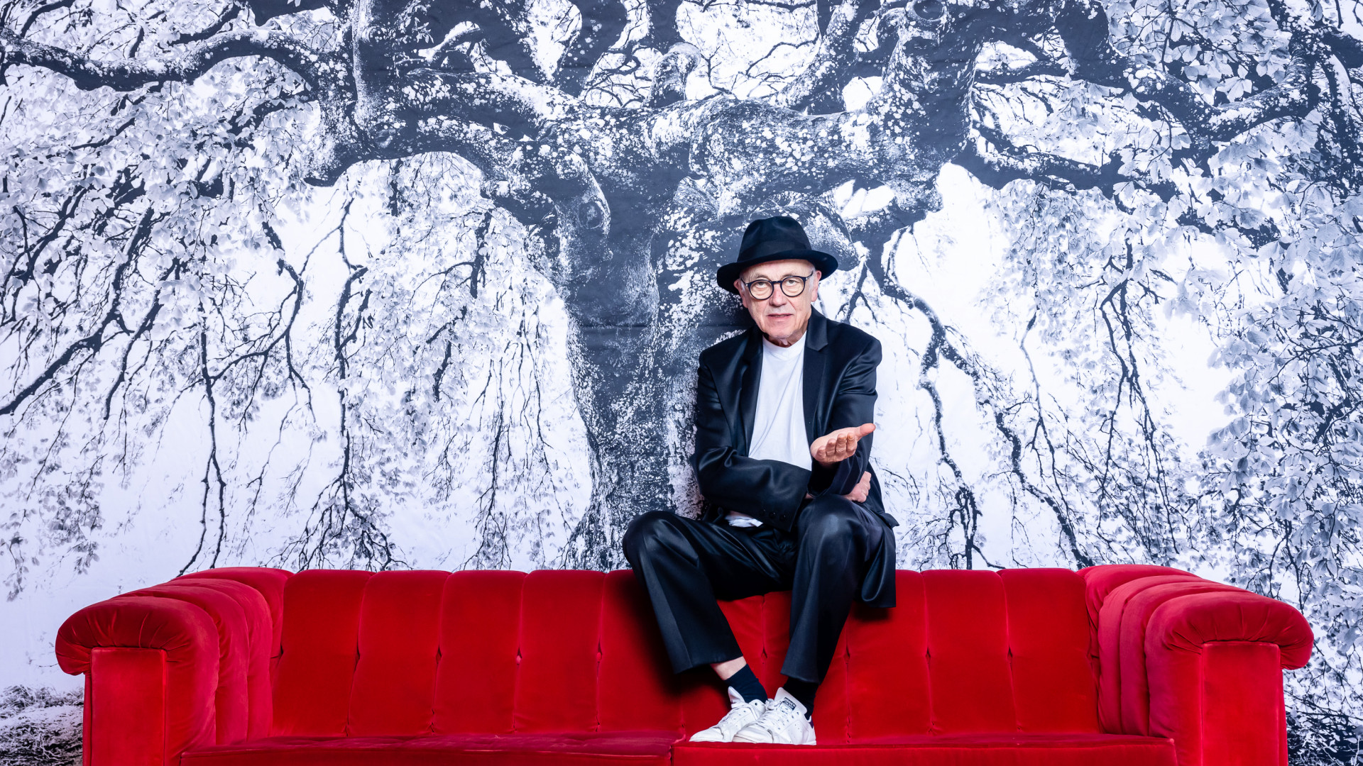 Fotograf und Künstler Horst Wackerbarth sitzt auf der roten Couch