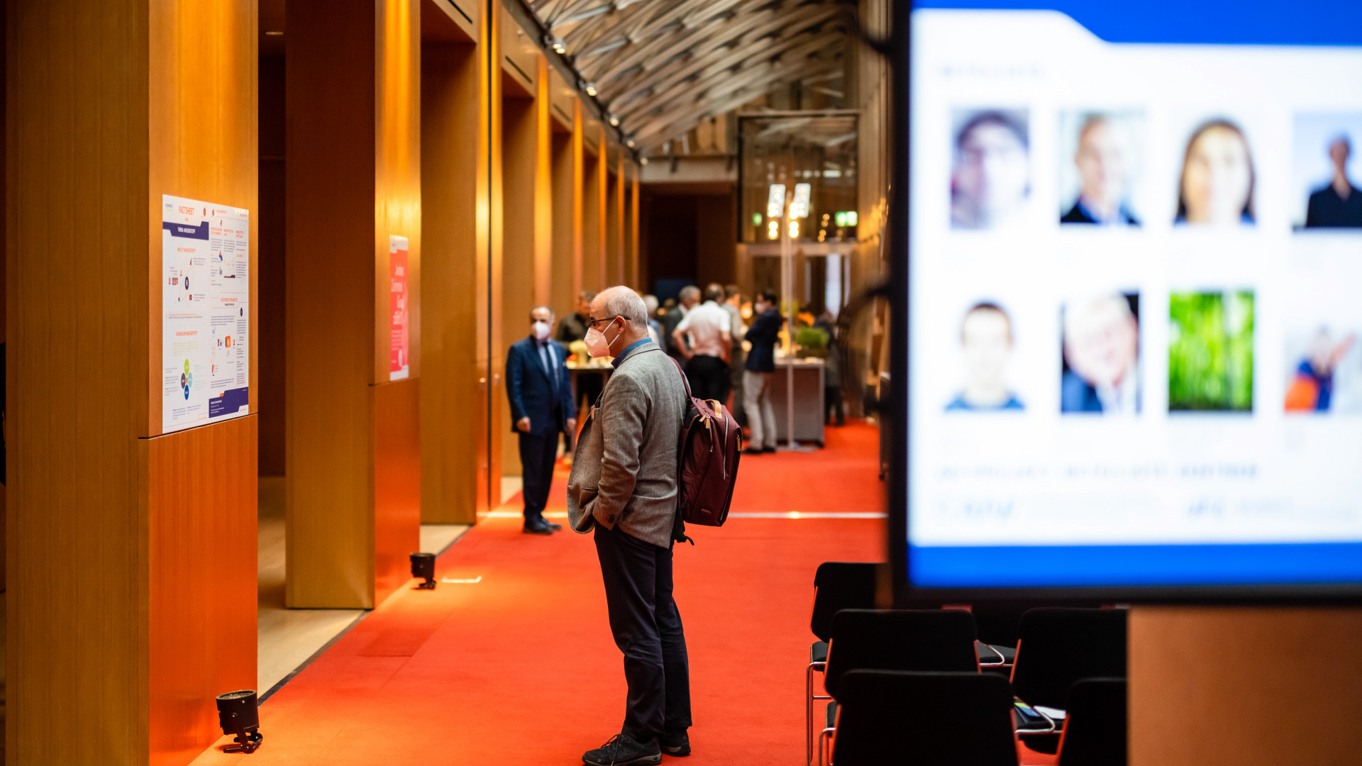 Konferenz-Teilnehmer:in steht vor einem Infoplakat