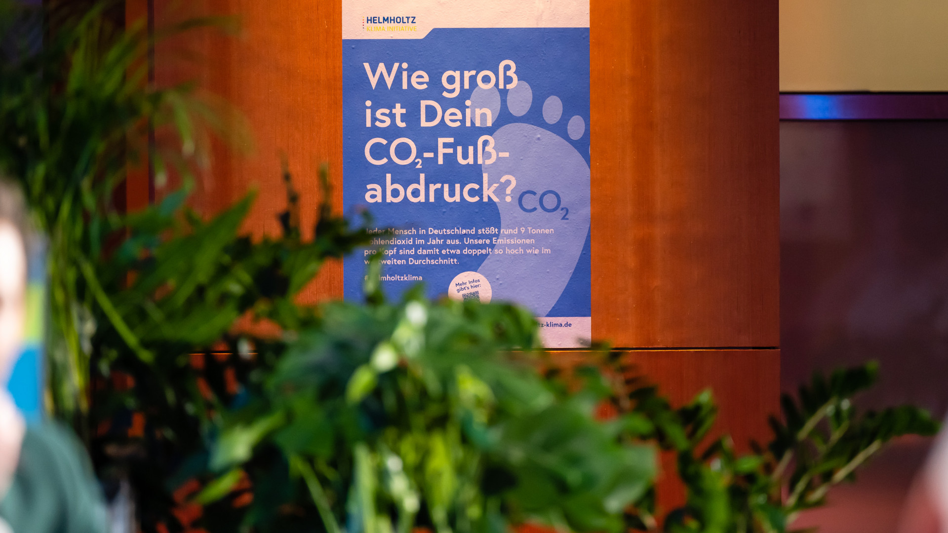 Das Plakat "Wie gross ist dein CO2-Fussabdruck" ist an einer Wand angebracht