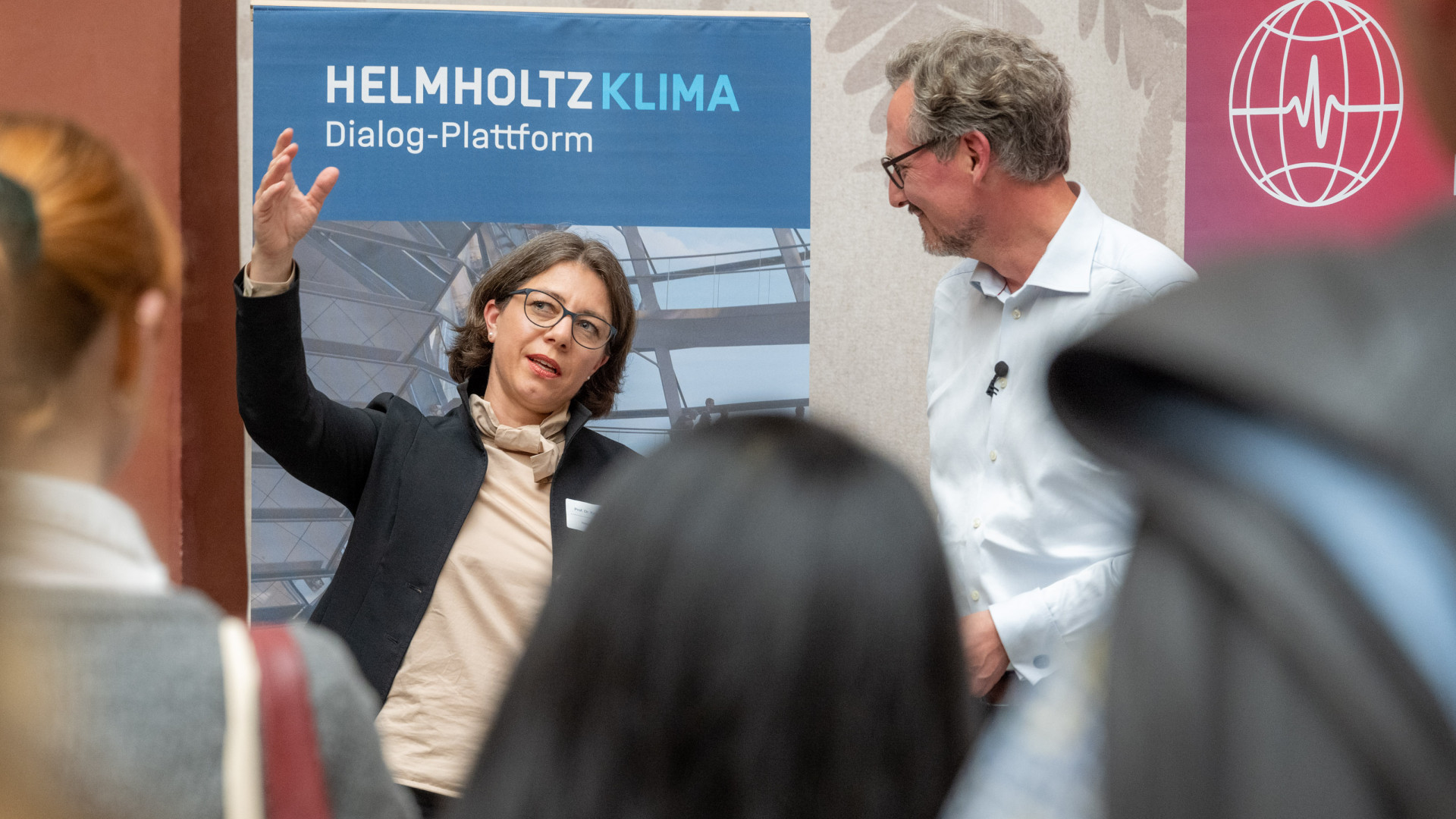 Zwei Personen im Austausch vor Publikum.