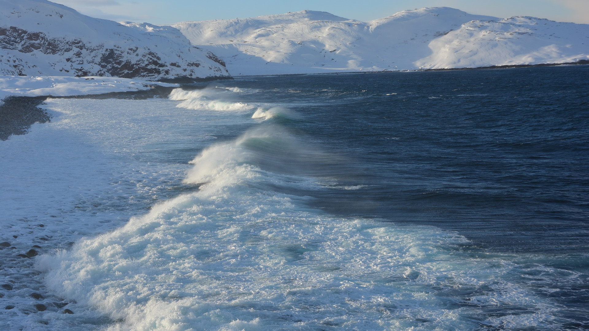 Eine Küste mit Ozean und schneebedeckten Bergen